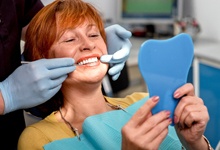 Woman in dental chair looking at her smile in the mirror